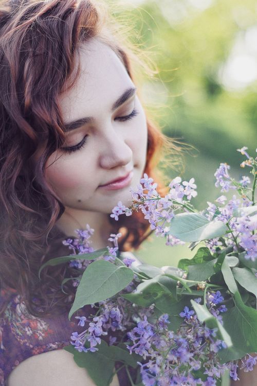 Free A woman enjoying the scent of lilac flowers in a serene outdoor setting. Stock Photo