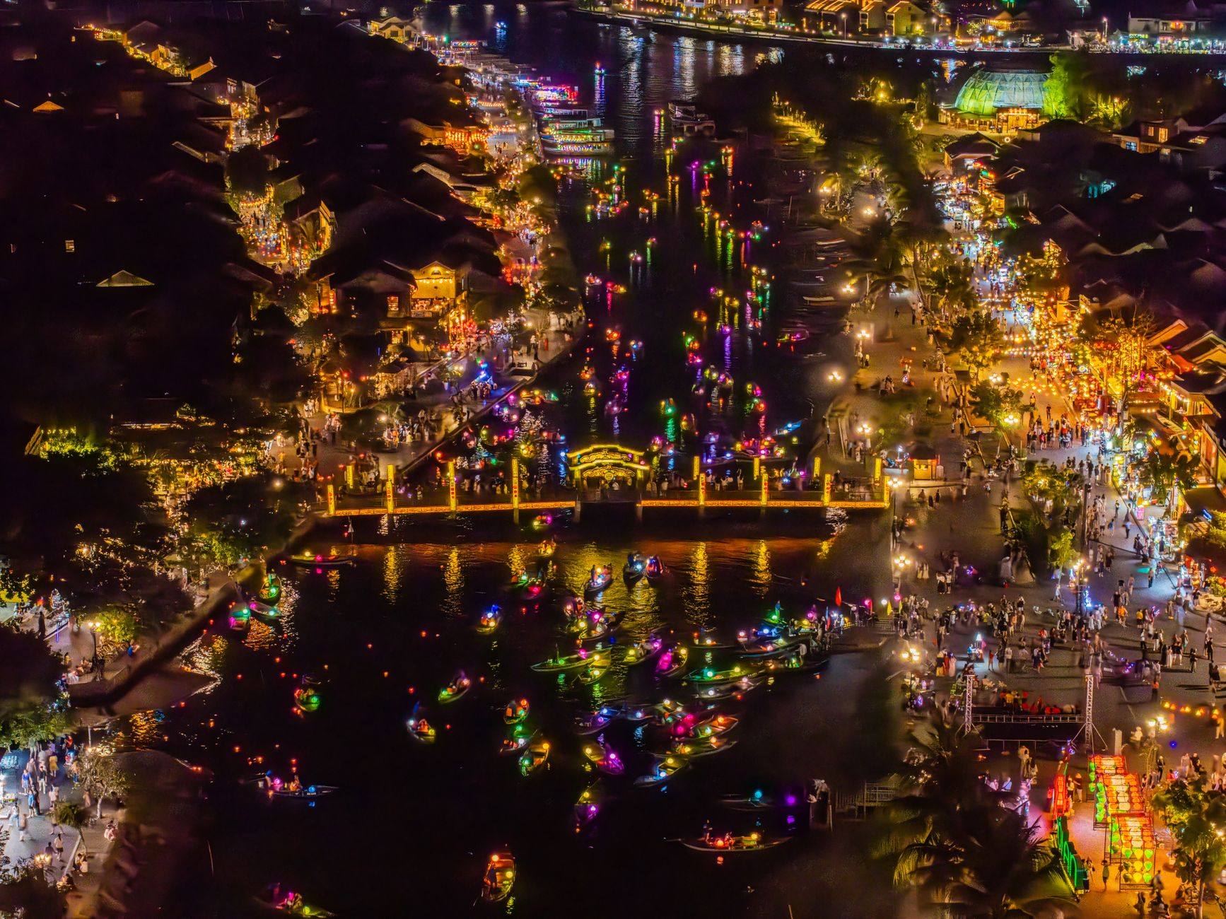 A vibrant aerial shot of Hội An's lantern festival, showcasing colorful lights and bustling waterfront.