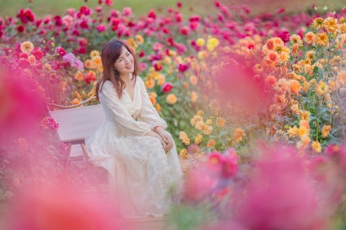 A woman sitting on a bench in a flower field