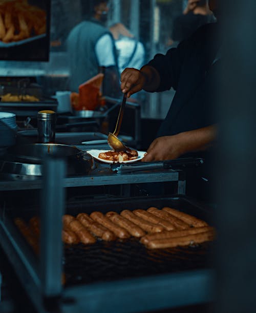 A man is cooking hot dogs on a grill