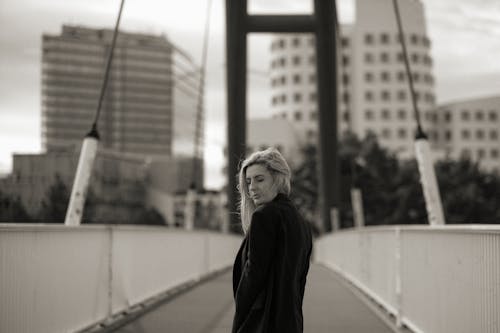 A woman standing on a bridge in black and white