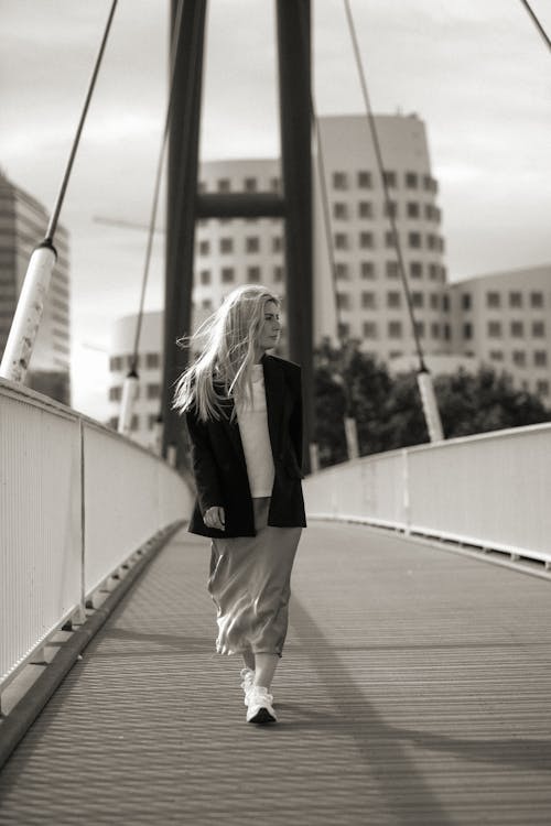 A woman walking across a bridge in black and white