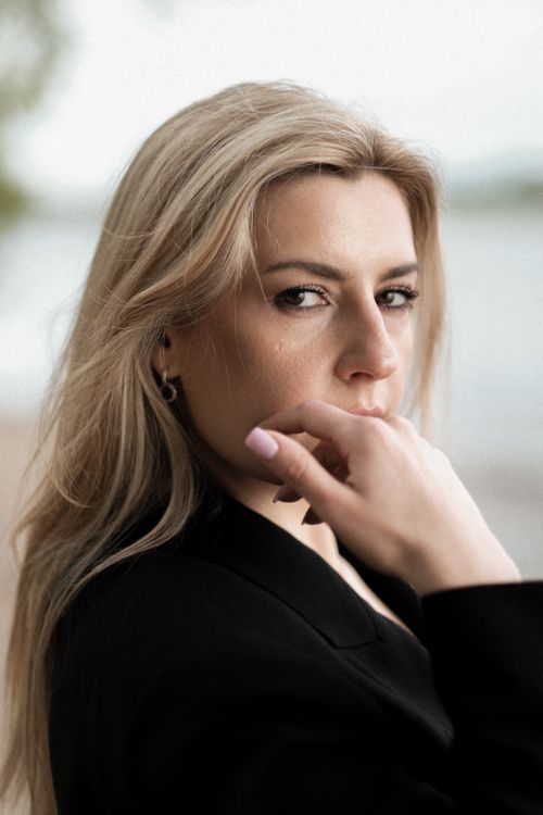 Free Close-up portrait of a blonde woman in a black blazer, thoughtful by the seaside. Stock Photo