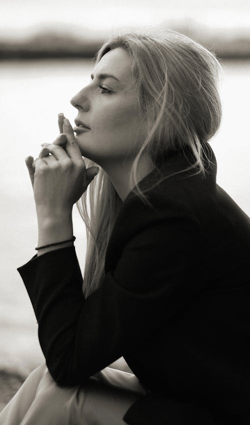 A woman sitting on a bench with her hand on her chin