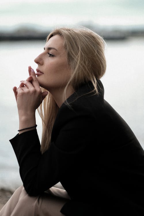 A woman sitting on the ground with her hand on her chin