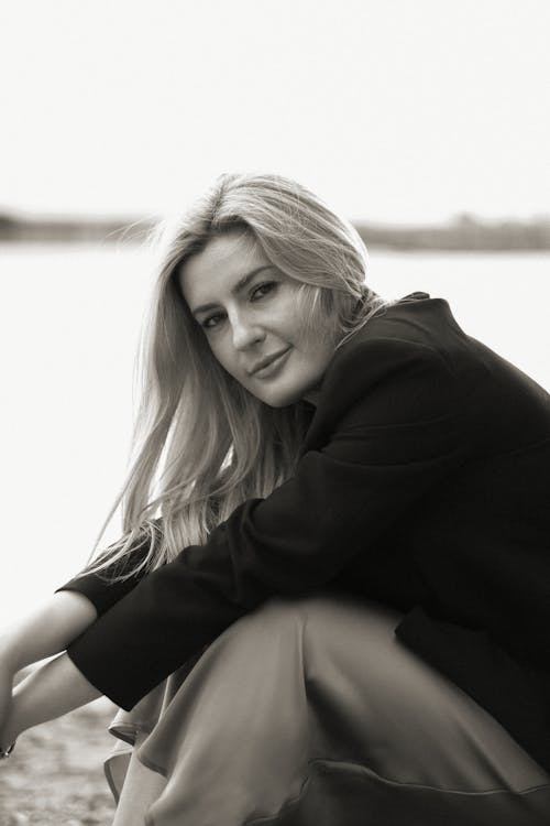 A woman sitting on the ground by the water