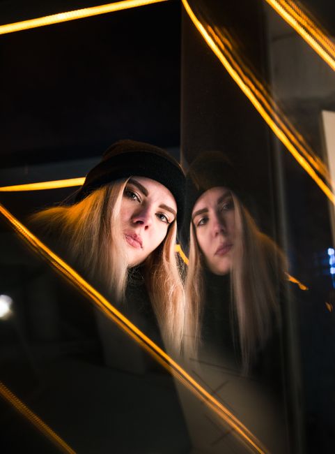 A visually compelling portrait of a woman reflecting against glass in Tallinn, Estonia, captured at night.