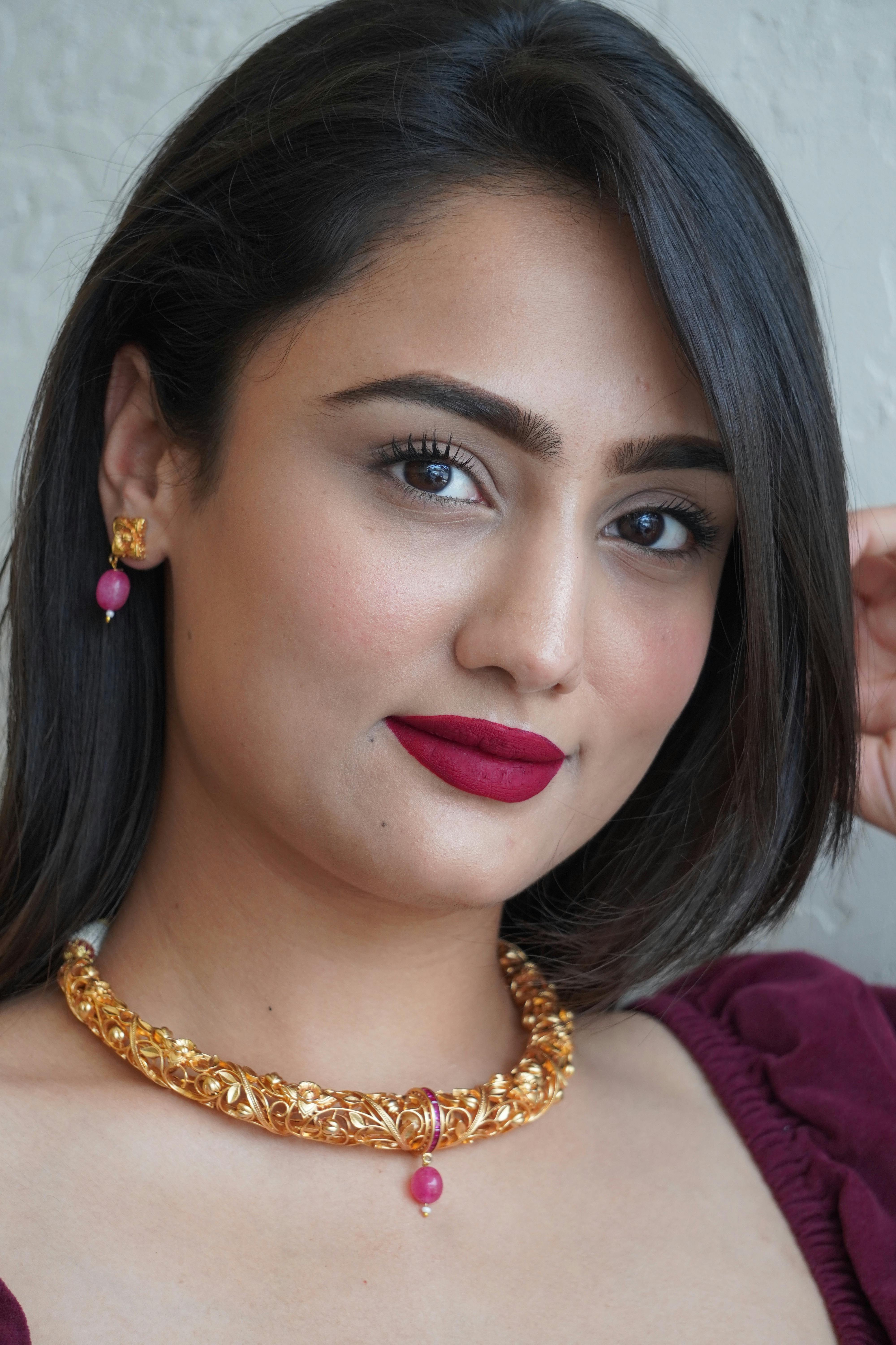 model in a gold necklace and earrings with pink stones