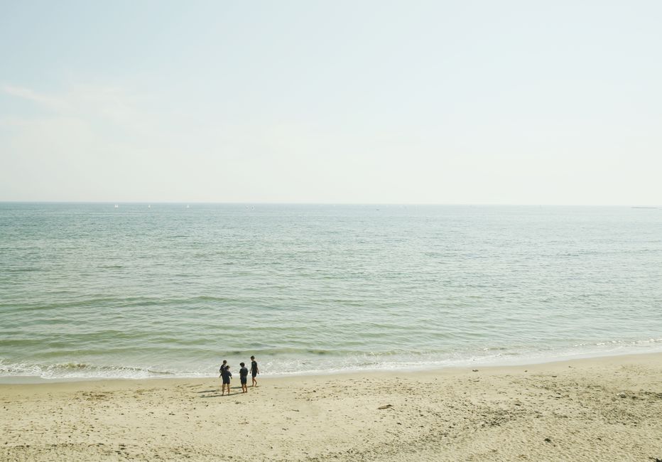 Three people enjoying a sunny day on a calm beach in Japan.