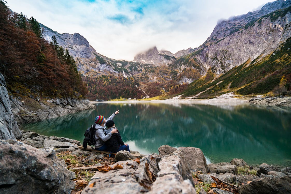 бесплатная Пара, сидящая на скале у озера Стоковое фото