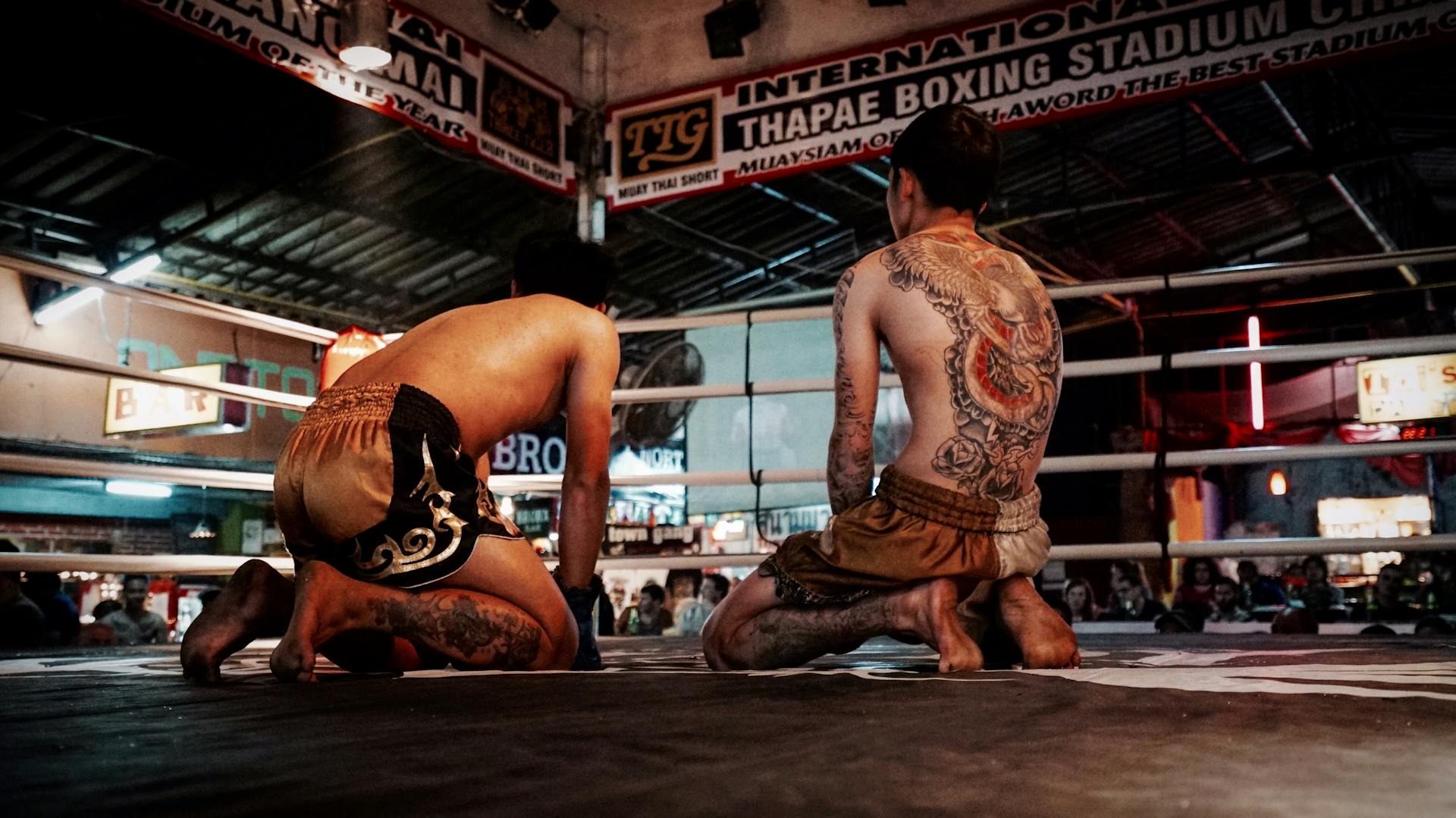 Mannen knäböjer på boxningsringen