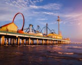 加尔维斯顿标志性的游乐码头上充满活力的日落，惊心动魄的游乐设施和海浪