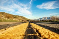 在明亮的蓝天下，从低视角看通往山脉的高速公路