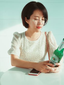 一位亚洲女性在咖啡馆里喝着喜力啤酒，享受室内的夏日时光