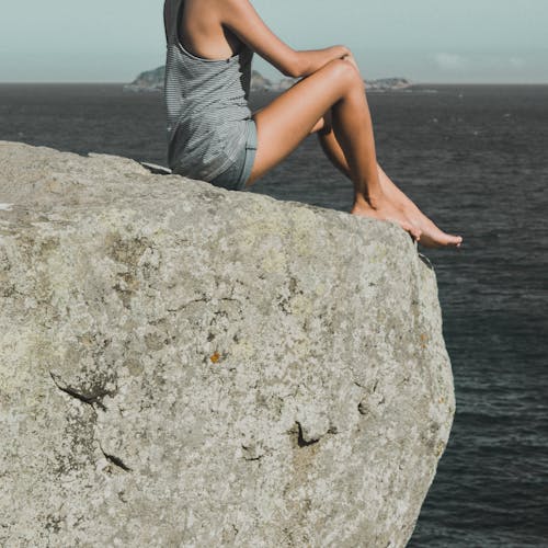 회색 돌에 앉아있는 여자