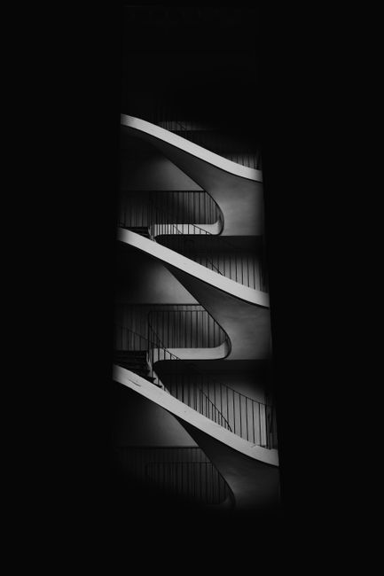 Dynamic black and white architectural abstract featuring curved stairs in Besançon, France.