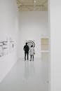 在极简主义的画廊环境中，两位参观者正在欣赏当代艺术品