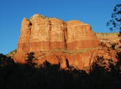 一块巨大的红色岩石矗立在清澈的蓝天下，宁静的自然风光被定格其中