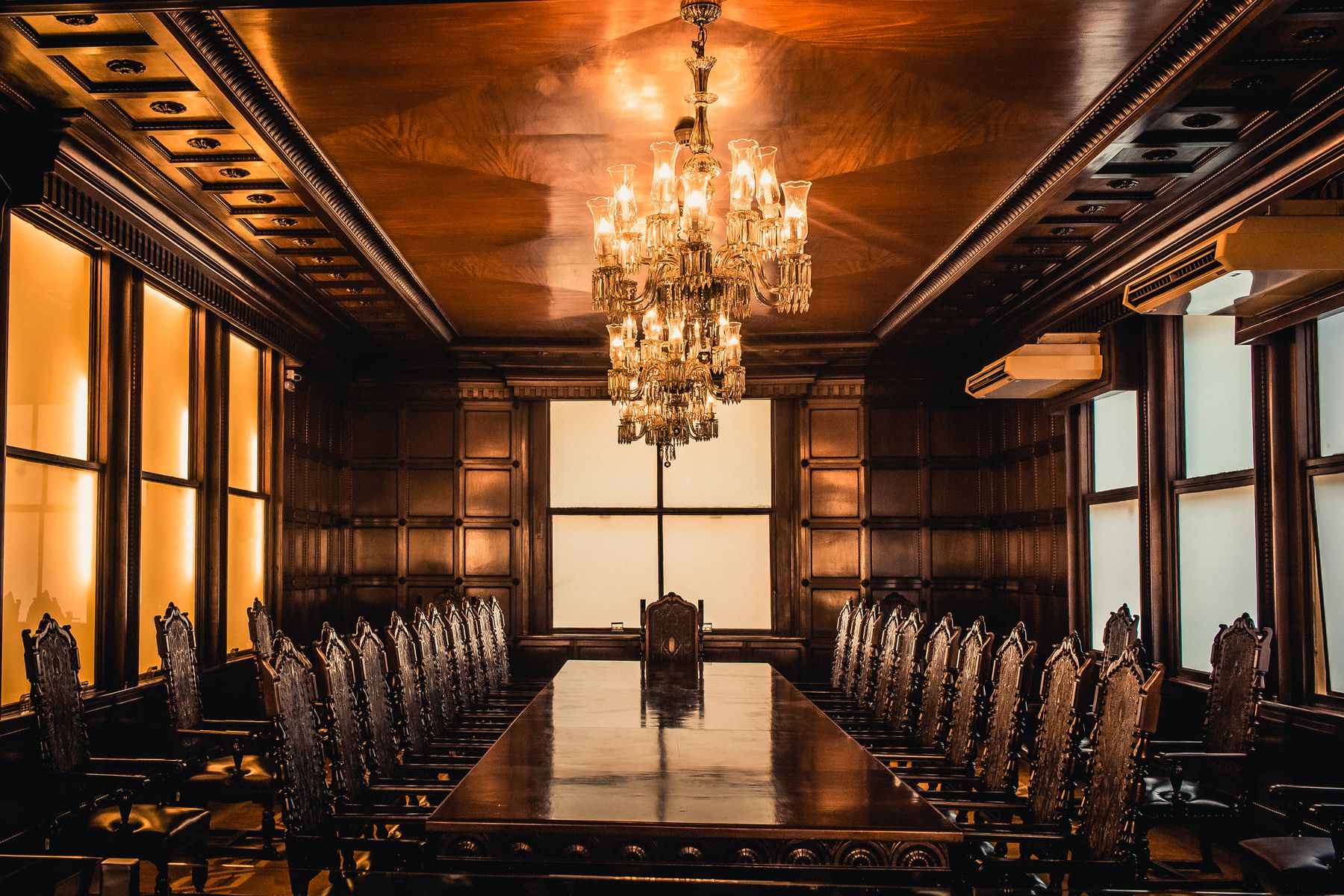 A wood-panelled boardroom lit by a crystal chandelier