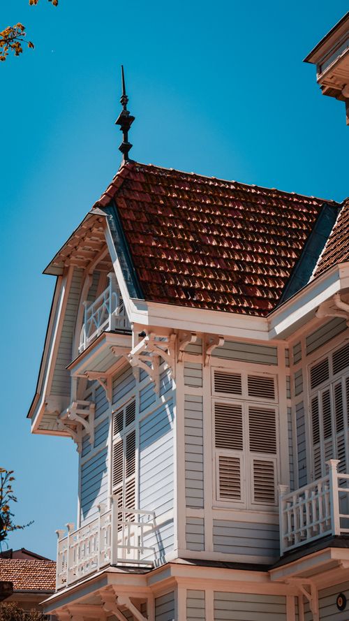 Free Elegant Victorian house with ornate details and red roof under a clear blue sky. Stock Photo