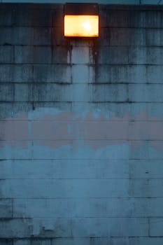 Calm urban scene featuring a weathered wall and illuminated outdoor light.