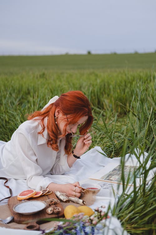 A woman sitting on a blanket in a field