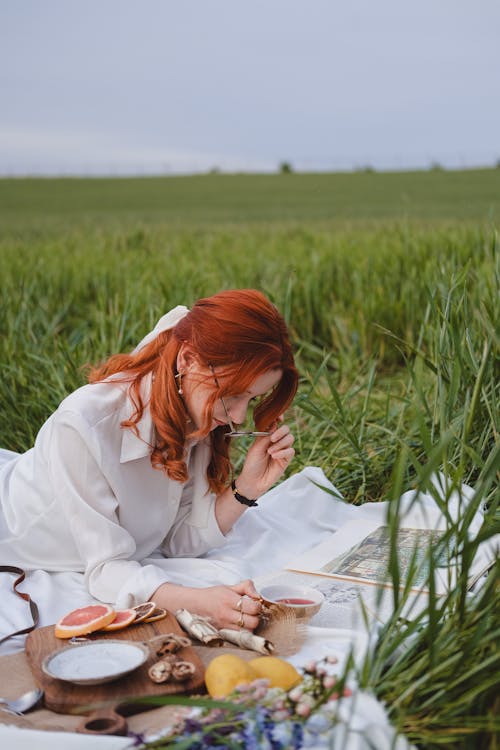 Free Woman in White Shirt Lying Down on Picnic and Reading Stock Photo