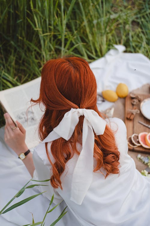 Free Back View of Redhead Woman Lying Down with Ribbon in Hair on Picnic Stock Photo