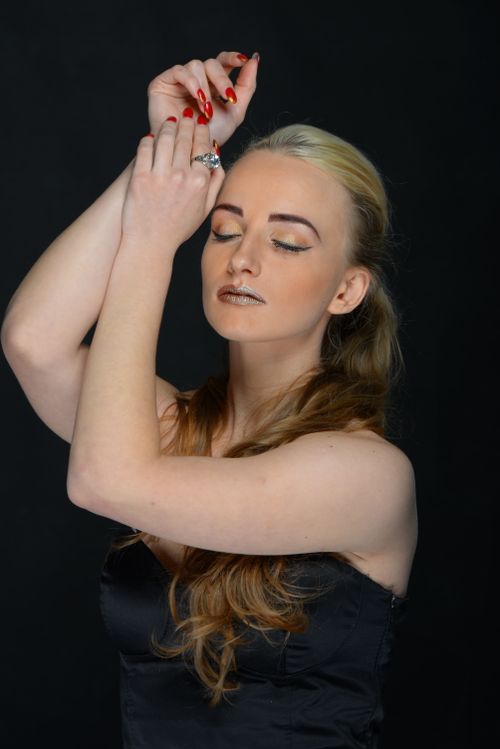 Free Stylish portrait of a woman with hands raised, eyes closed against a black background. Stock Photo