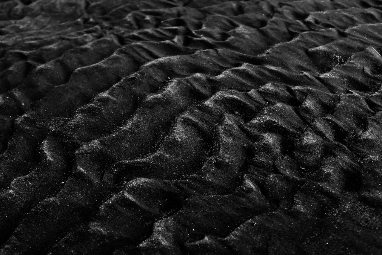 close up of textured black sand dunes in monochrome showcasing natural