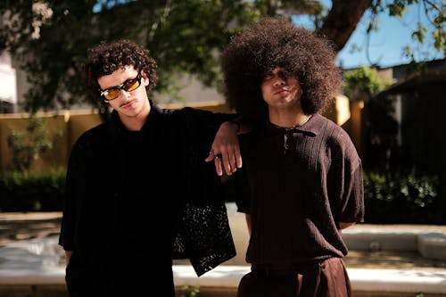 Two men with curly hair standing next to each other