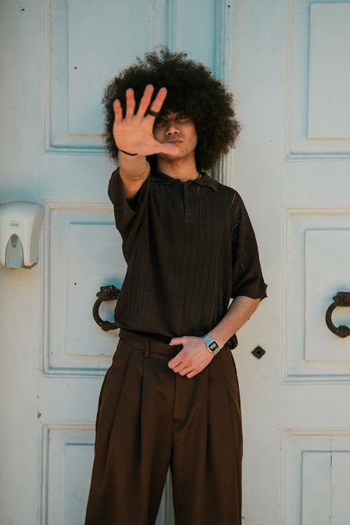A man with an afro wearing a brown shirt and pants