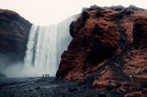 Three Men Standing Near Waterfalls