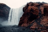 Three Men Standing Near Waterfalls