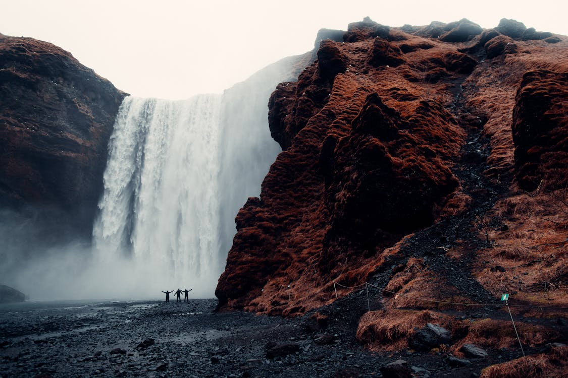 Three men standing near waterfalls