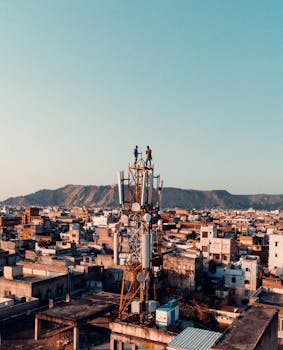 日落时分，两个人站在电信塔顶鸟瞰城市景观