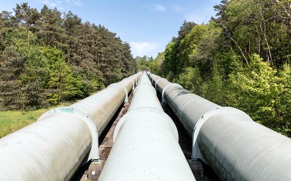 A large industrial pipeline running through open countryside — photo by Wolfgang Weiser on Pexels