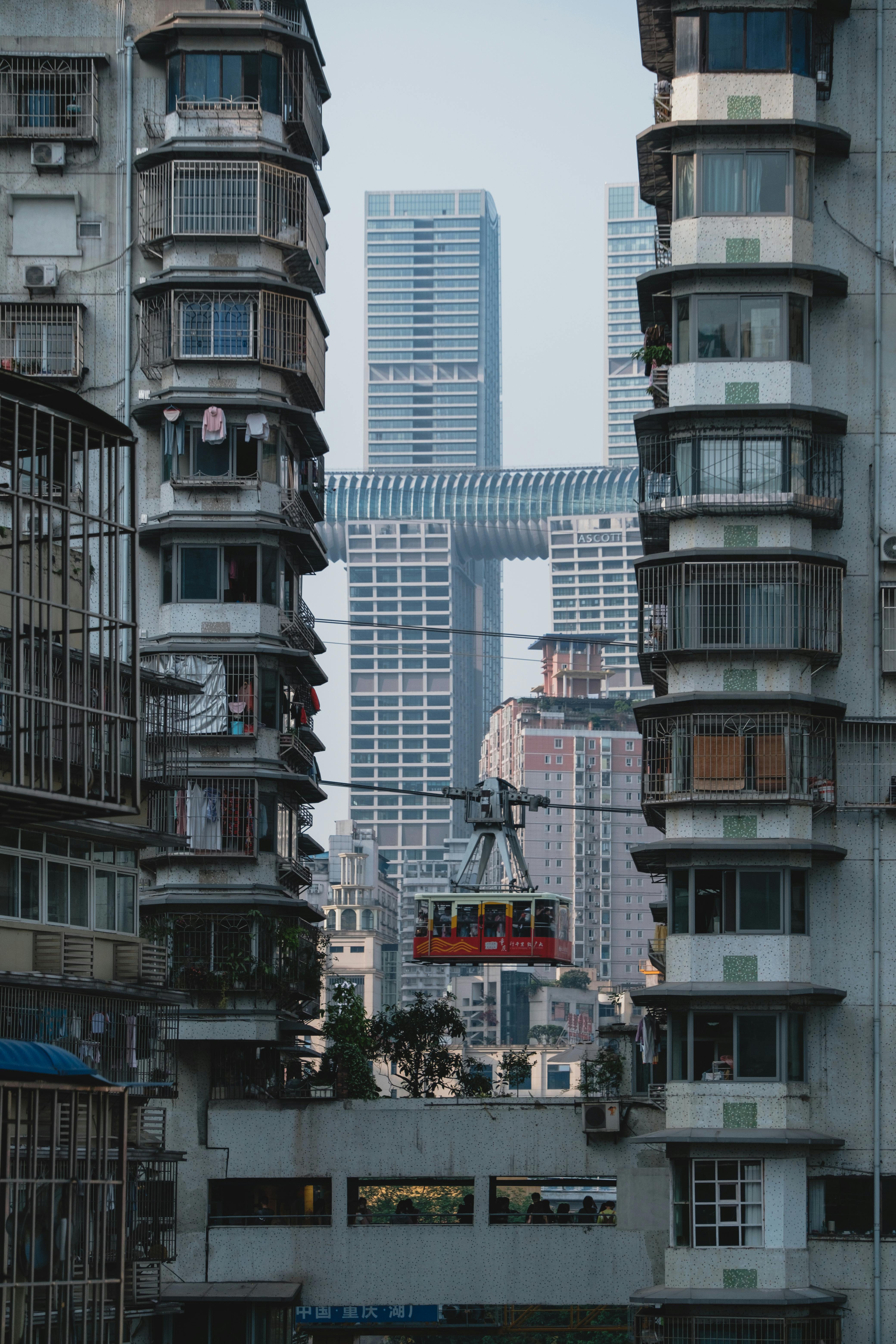 A bustling cityscape with a cable car passing between modern skyscrapers and older buildings.