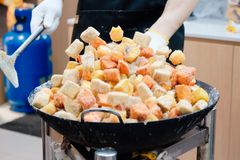 Vendor frying colorful tofu cubes at an Asian market stall. Captured in an urban setting, showcasing vibrant street food culture.