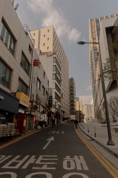 A quiet city street in Seoul lined with tall buildings under a clear sky.