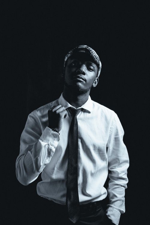 Free Elegant black and white portrait of a young man in a studio, dressed in a shirt and tie, exuding confidence. Stock Photo
