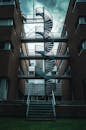 一张展现城市建筑中现代建筑间螺旋楼梯的忧郁照片