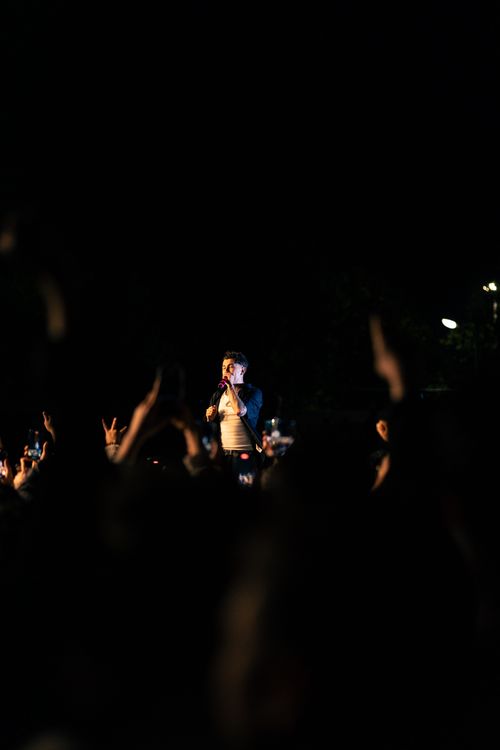 Free Vibrant night concert scene with singer engaging the audience on stage among bright lights. Stock Photo