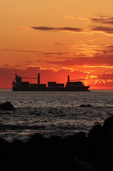 Silhouetted cargo ship on Atlantic Ocean during sunset in Porto, Portugal.