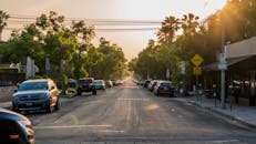 宁静的城市街道上，日落时分，汽车停放在郁郁葱葱的绿树旁