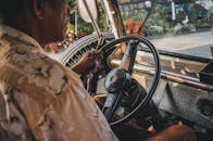 一个男人专注地驾驶着一辆老爷车，目光紧盯着仪表板和方向盘