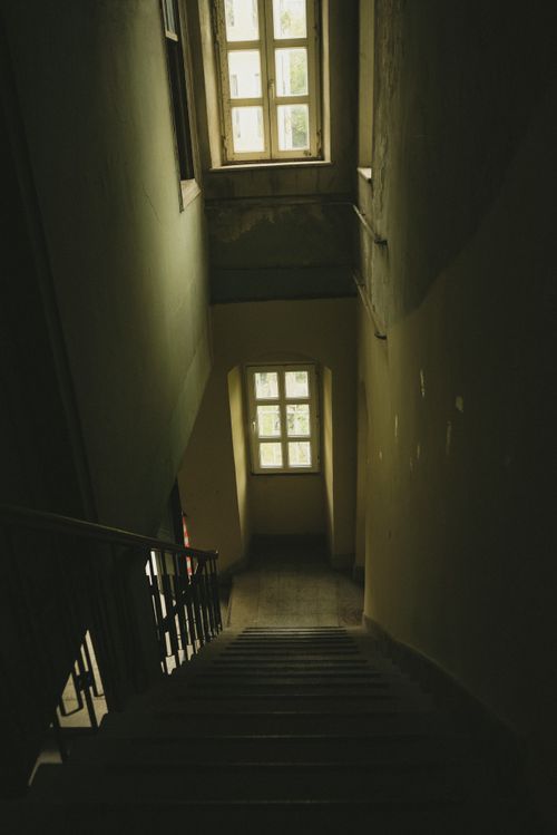 Free Explore the eerie atmosphere of an abandoned staircase in dim lighting with visible windows. Stock Photo
