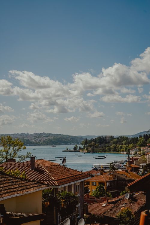 Free A stunning aerial shot capturing a vibrant coastal town with red rooftops and a serene harbor under a clear sky. Stock Photo