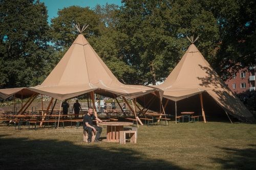 Free Outdoor scene featuring large tents, benches, and tables on a sunny summer day. Stock Photo