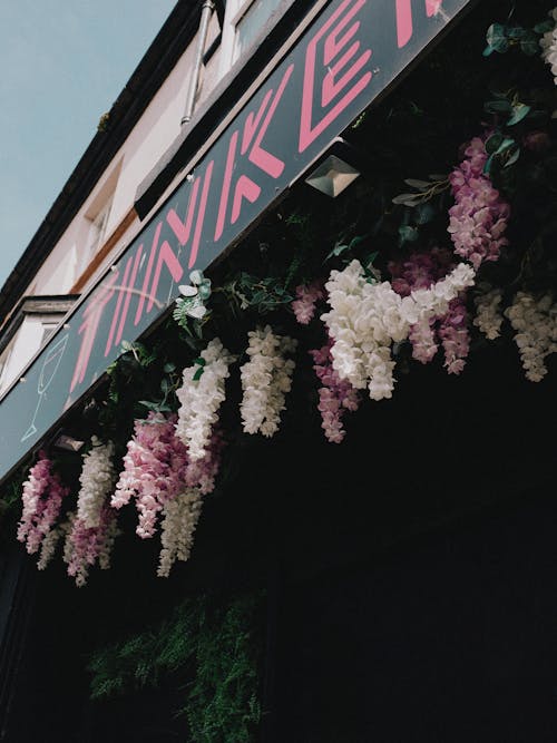 A flower covered sign with purple flowers hanging from it